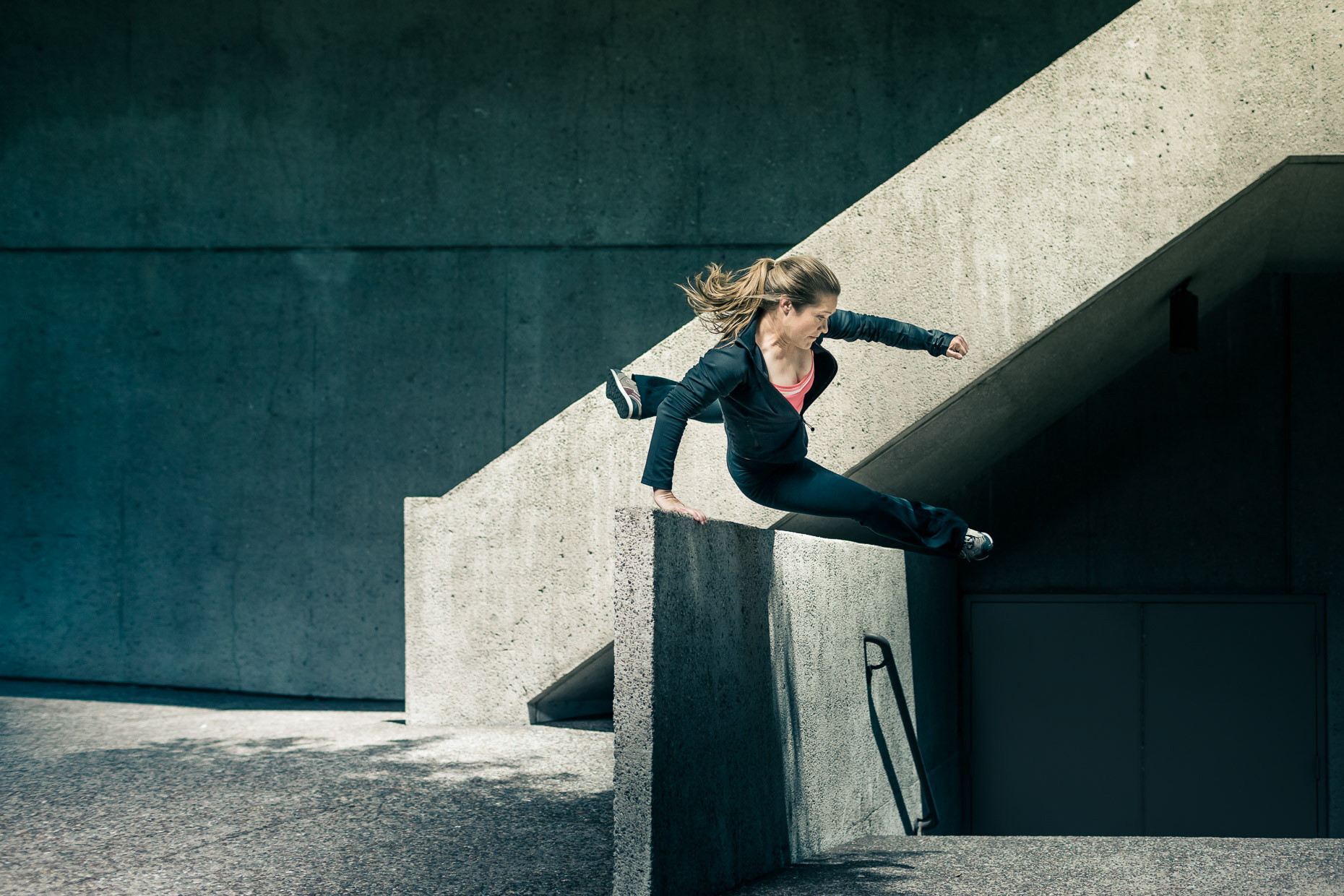 Luci Romberg freerunner parkour athlete leaping over concrete barrier wall in downtown LA by andy batt
