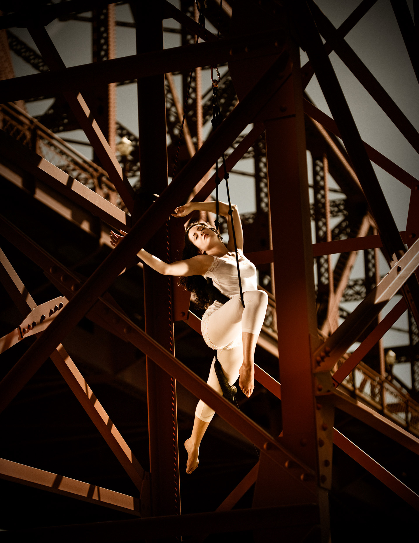 trapeze artist performing from Broadway Bridge with artist Sy Parrish in white leotard  by andy batt