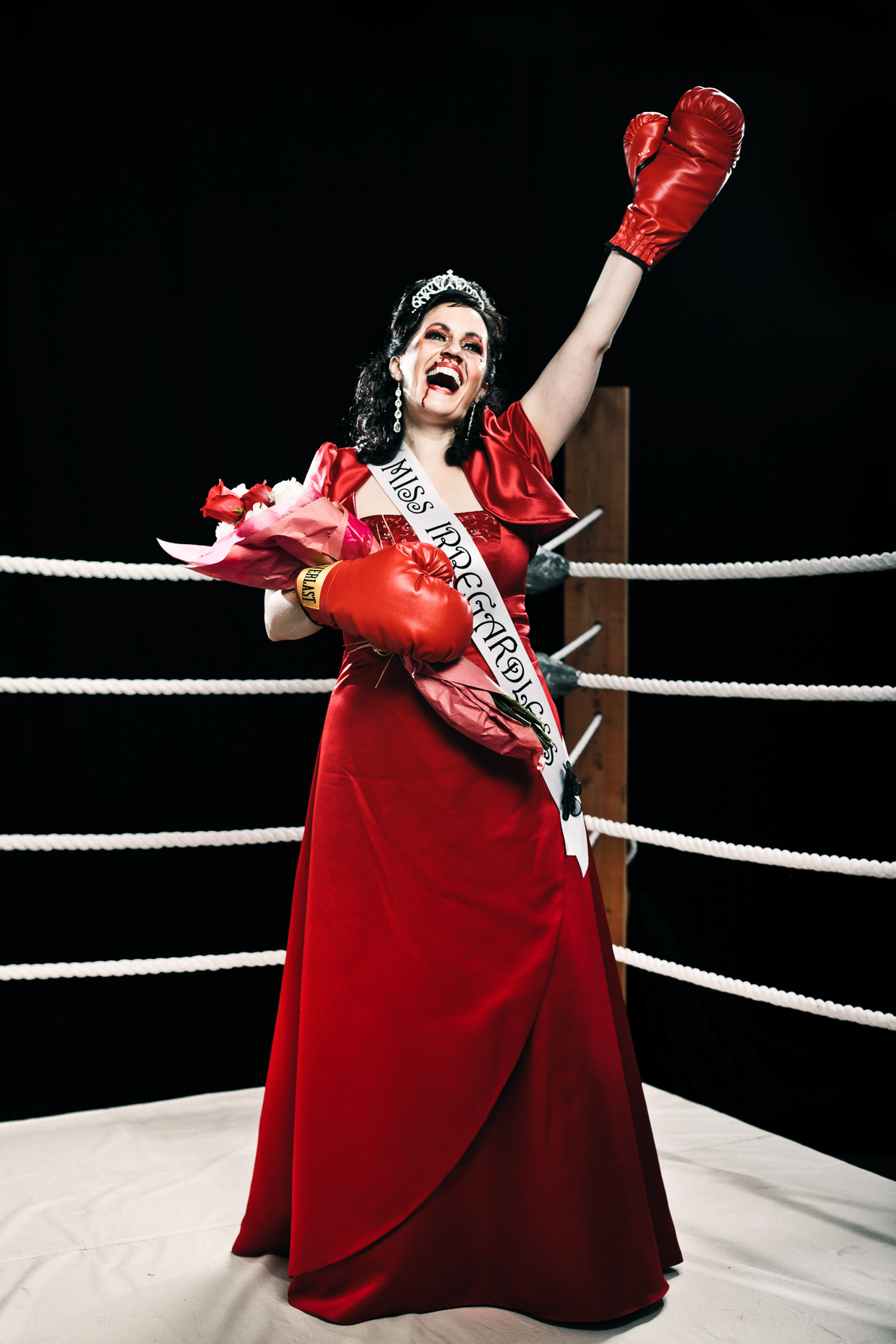 Editorial portrait of Stacey Hallal as a beauty pagaent queen in the  "Miss Irregardless" boxing talent competition at the Curious Comedy Theater in Portland, Oregon. Poster art by Andy Batt