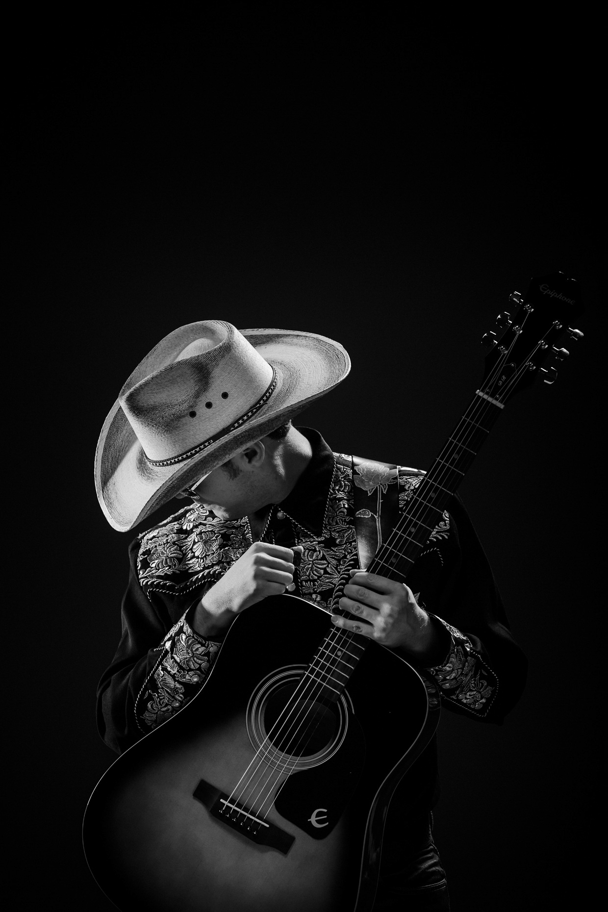 Musical artist Chase Padgett in a pensive pose wearing a cowboy hat and hoding his guitar for poster art of his one man show,  Nashville Hurricane by Andy Batt