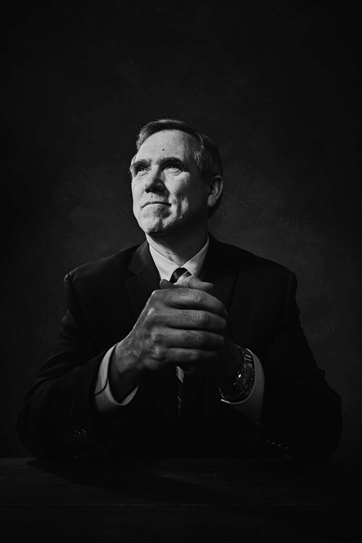 B&W Editorial portrait of Oregon senator Jeff Merkley in a formal pose holding his hands thoughtfully for Portland Monthly Magazine by Andy Batt