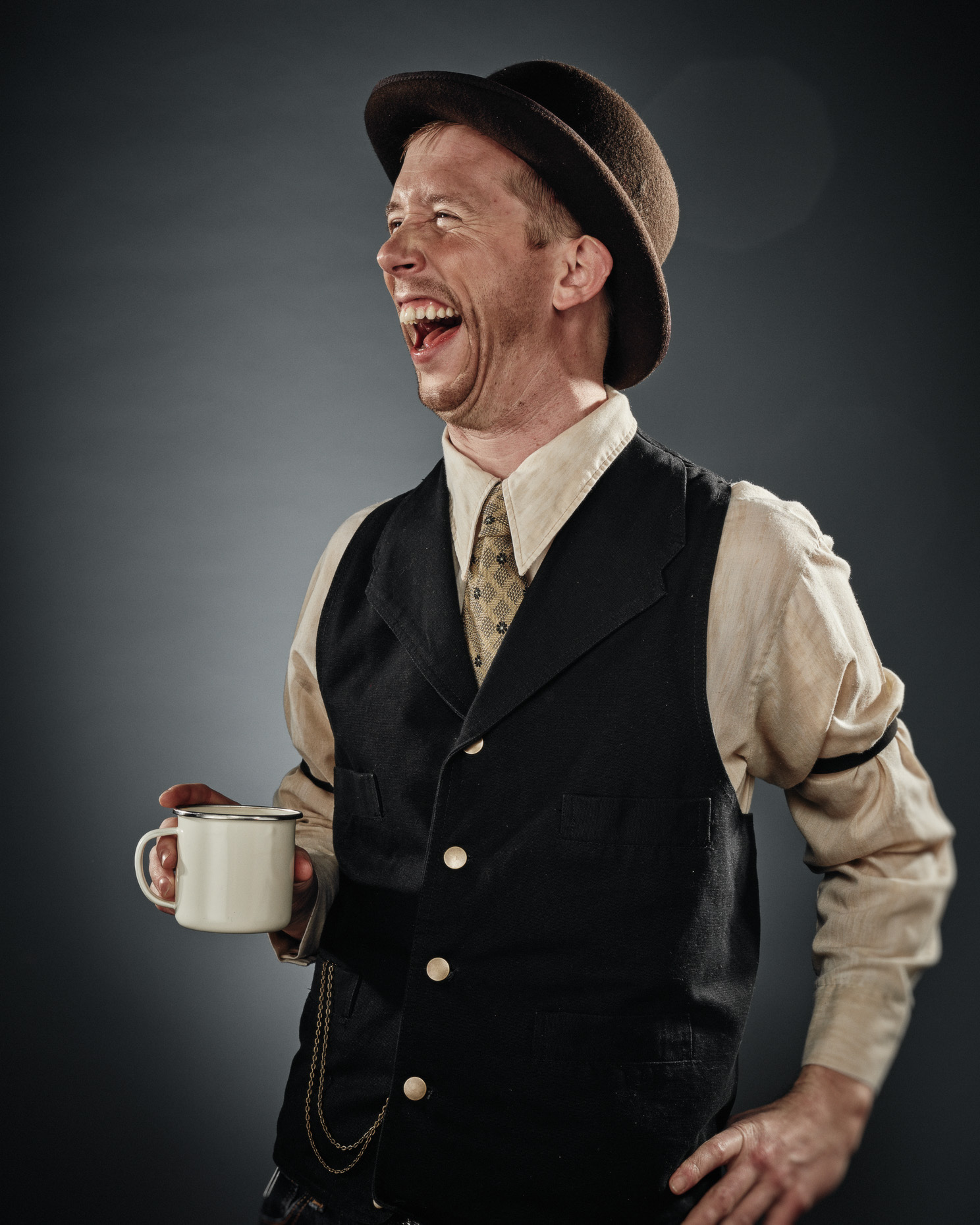 In studio character portrait of improv actor Chad Parsons Curious Comedy Theater Showdown dressed as a saloon bartender holding a metal coffee cup. Photo by Andy Batt