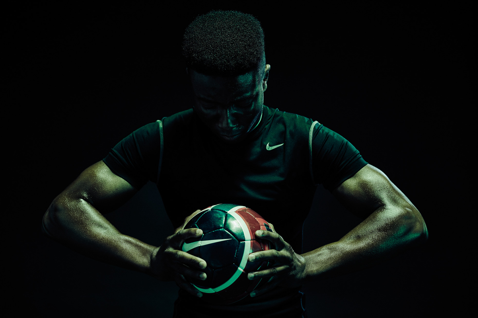 Nike soccer futbol Versace Sonachi holding the ball in a dark scene lit wiht green and blue gels by Andy Batt