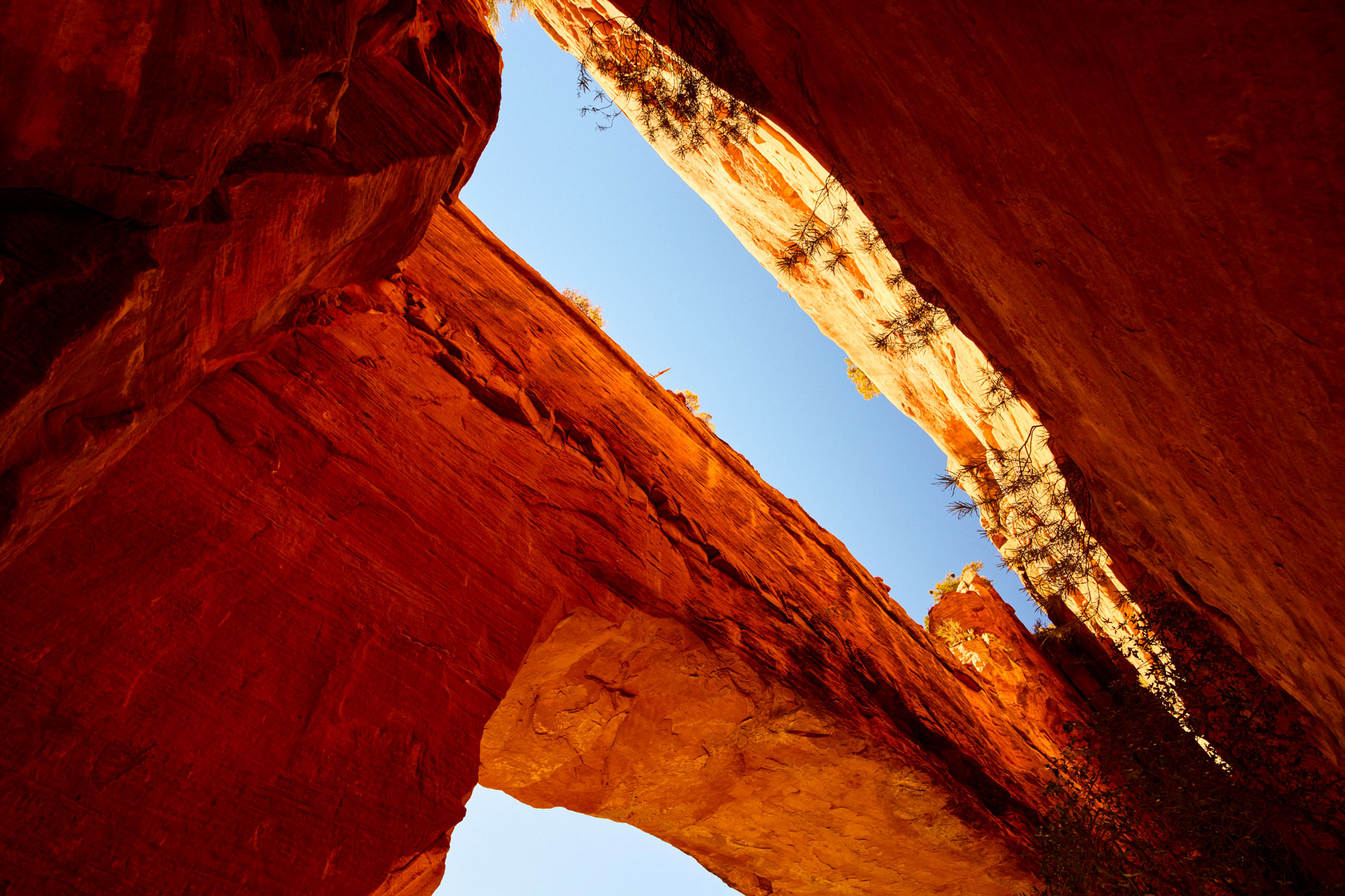 looking up natural bridge formation midday light and blue sky